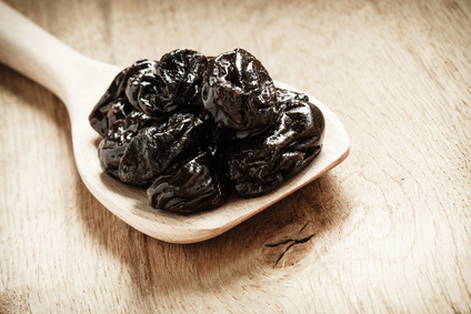 dried plums prunes on wooden spoon