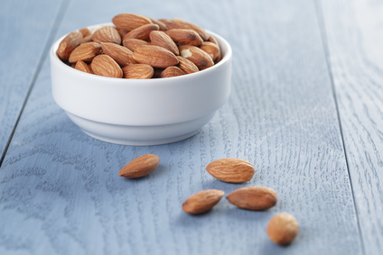 roasted almonds in white bowl on wooden table